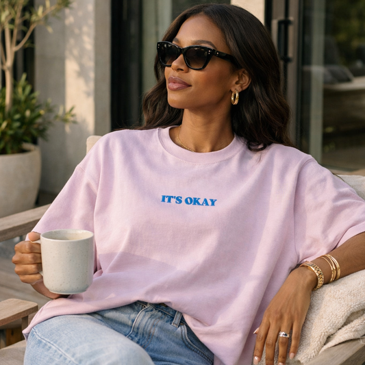 African American woman wearing lavender It’s Okay Comfort Colors women’s boxy tee styled with jeans and gold jewelry, relaxed lifestyle outfit for everyday wear