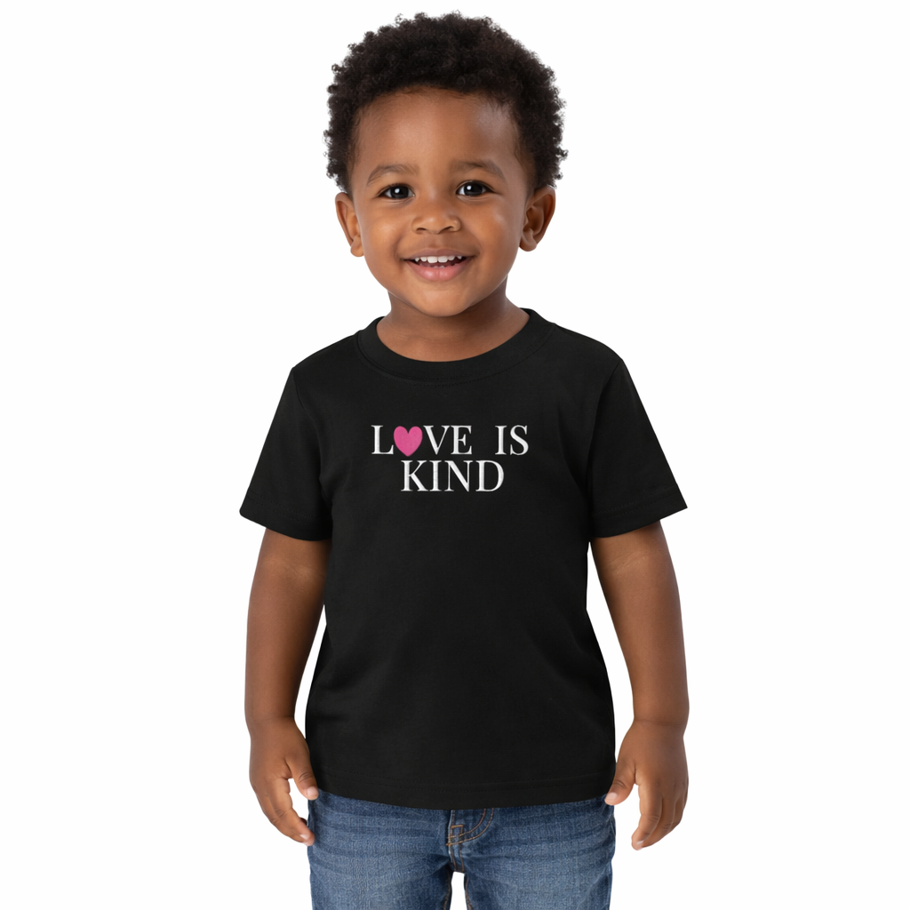 black toddler tee with text that reads love is kind embroidered in white text with a pink heart 