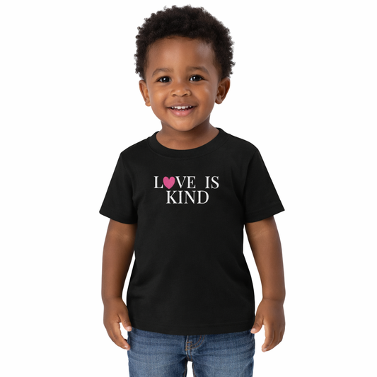 black toddler tee with text that reads love is kind embroidered in white text with a pink heart 